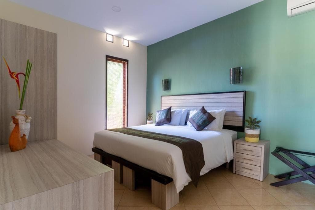 a bedroom with a large bed with a blue wall at Benian Villas in Nusa Dua