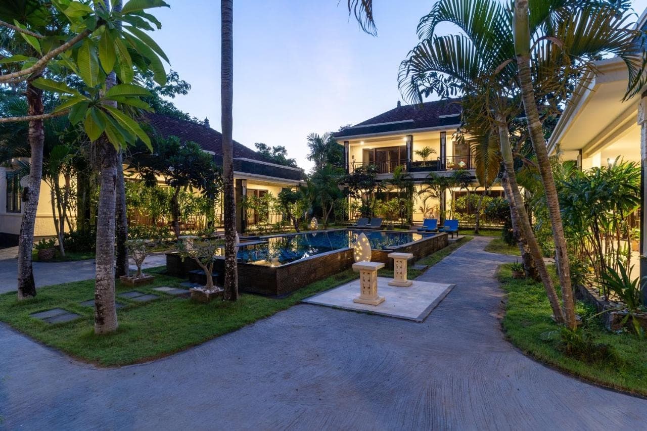 a resort with a swimming pool and palm trees at Benian Villas in Nusa Dua