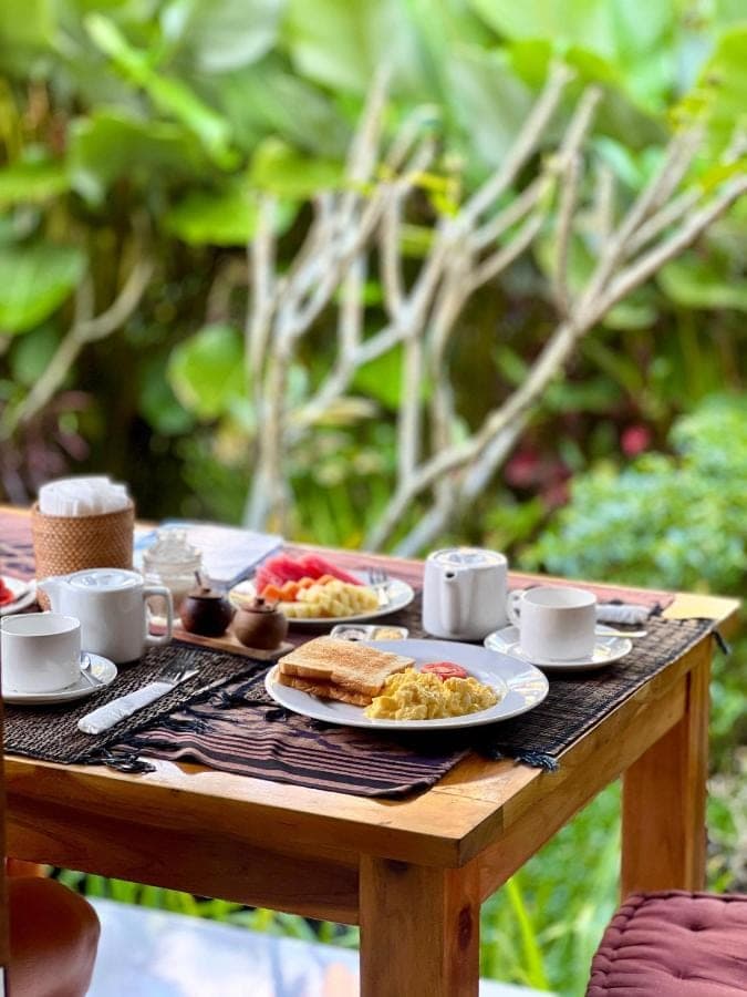 a wooden table with breakfast food on it at Buntera Homestay Sidemen in Sidemen