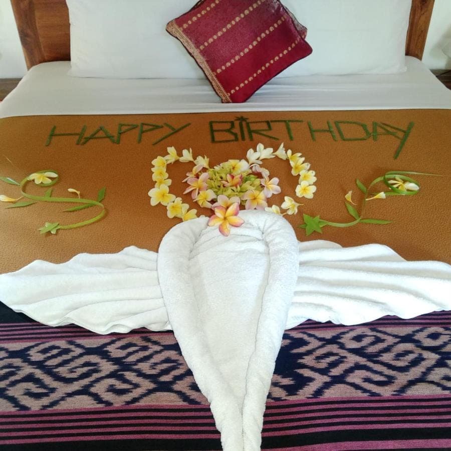a bed with a happy birthday sign and towels on it at Buntera Homestay Sidemen in Sidemen