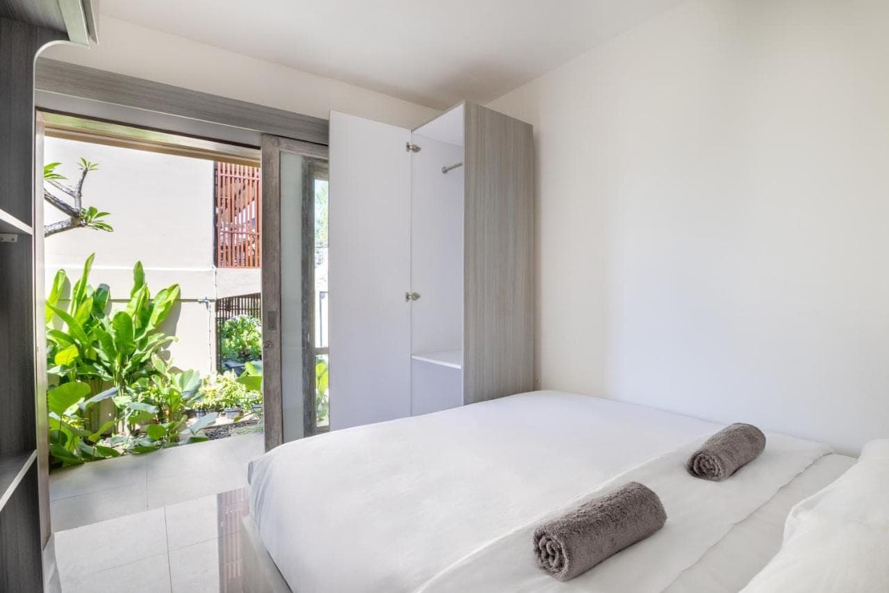 a bedroom with a white bed and a glass shower at Home-Bience Hostel in Uluwatu