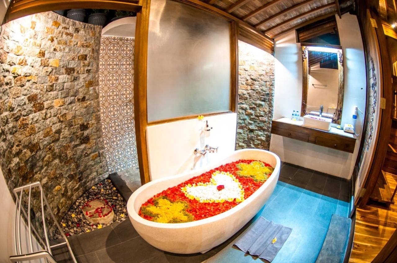 a bathroom with a large bath tub filled with flowers at Puri Kobot Ubud in Ubud