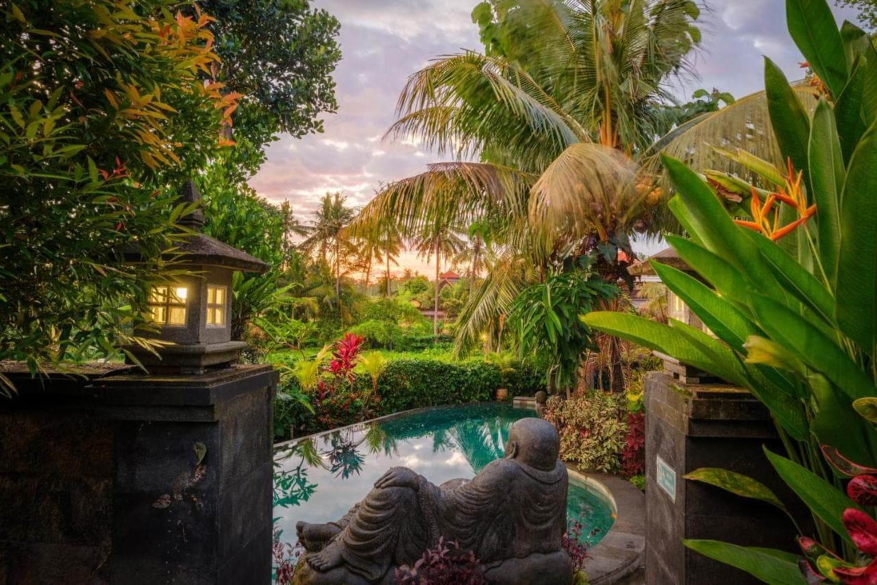 a garden with a statue next to a pool at Puri Kobot Ubud in Ubud