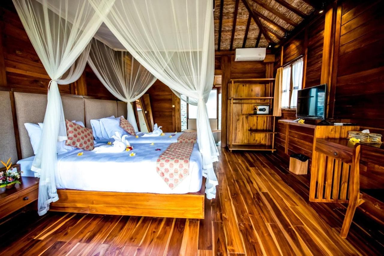 a bedroom with a bed with curtains and a television at Puri Kobot Ubud in Ubud