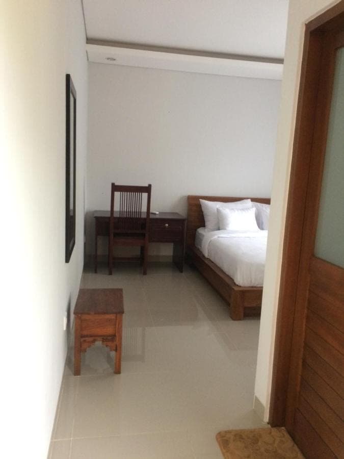 a bedroom with a bed and a chair and a table at UmahOde Bali in Nusa Dua
