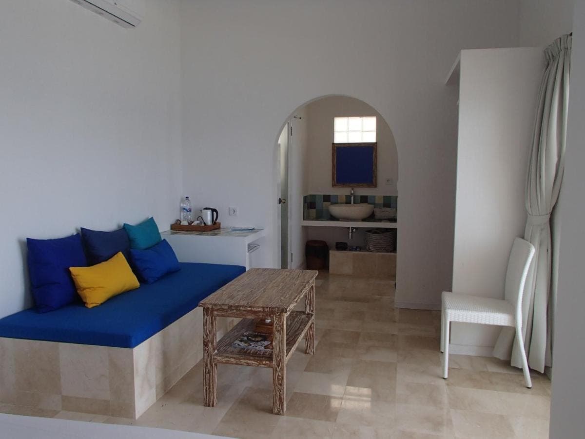 a living room with a blue couch and a table at Aquaterrace Amed in Amed
