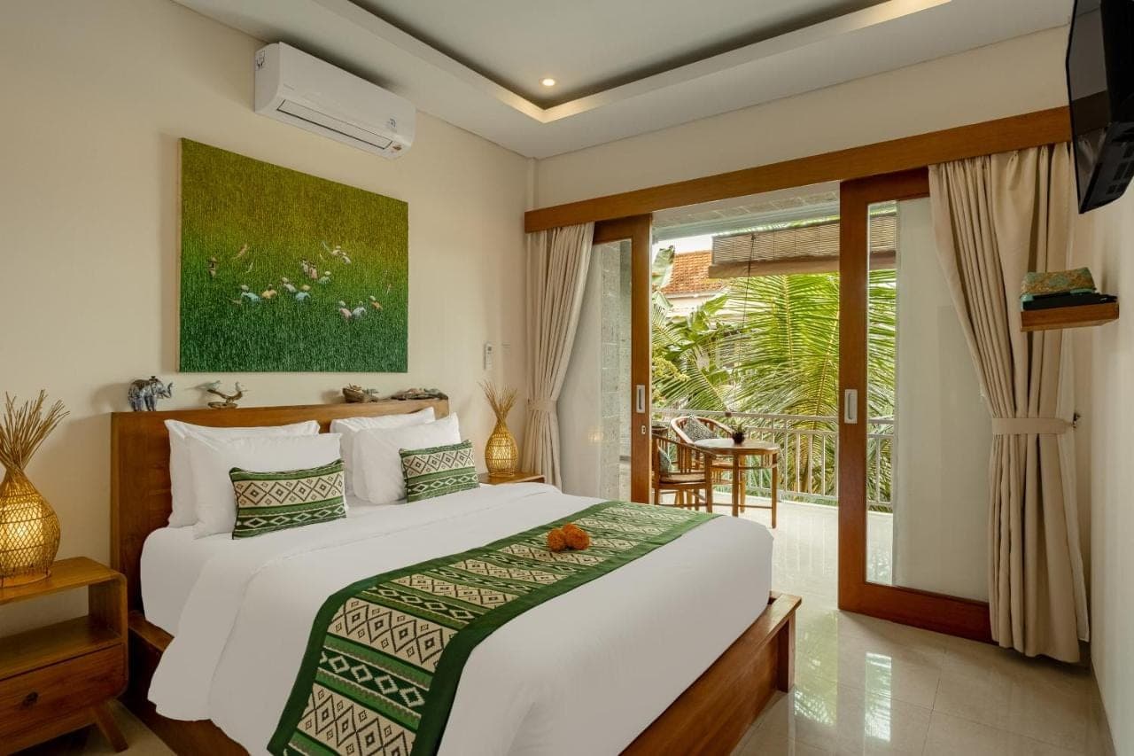 a bedroom with a bed and a sliding glass door at Orchid Ubud Cottage in Ubud