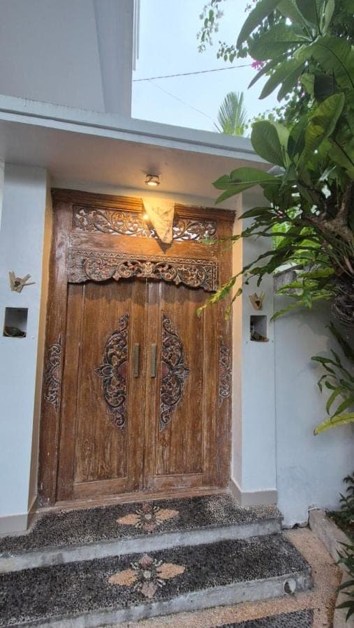 a large wooden door on a building with stairs at Laksmi Guest House in Canggu