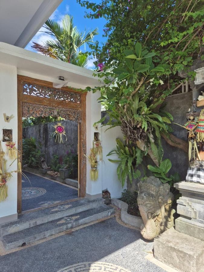 an entrance to a house with a gate and a tree at Laksmi Guest House in Canggu