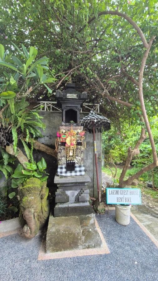 a small shrine in a park with a sign at Laksmi Guest House in Canggu