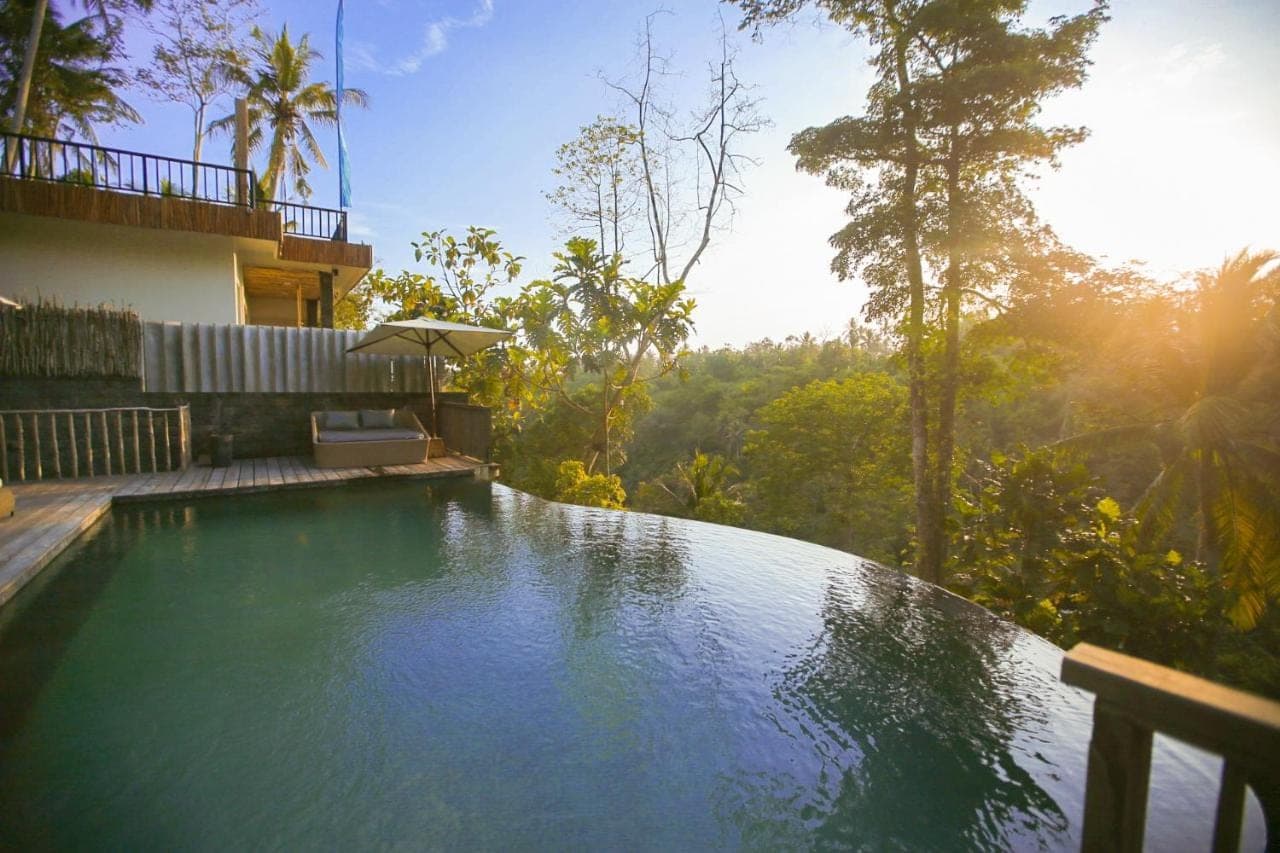 a swimming pool in front of a house at Angsoka Bungalow in Ubud