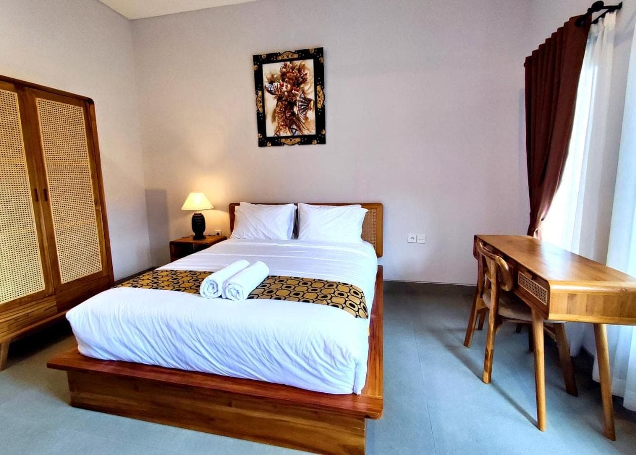a bedroom with a bed and a desk and a bed sidx sidx sidx at Vinandaka Homestay in Sanur