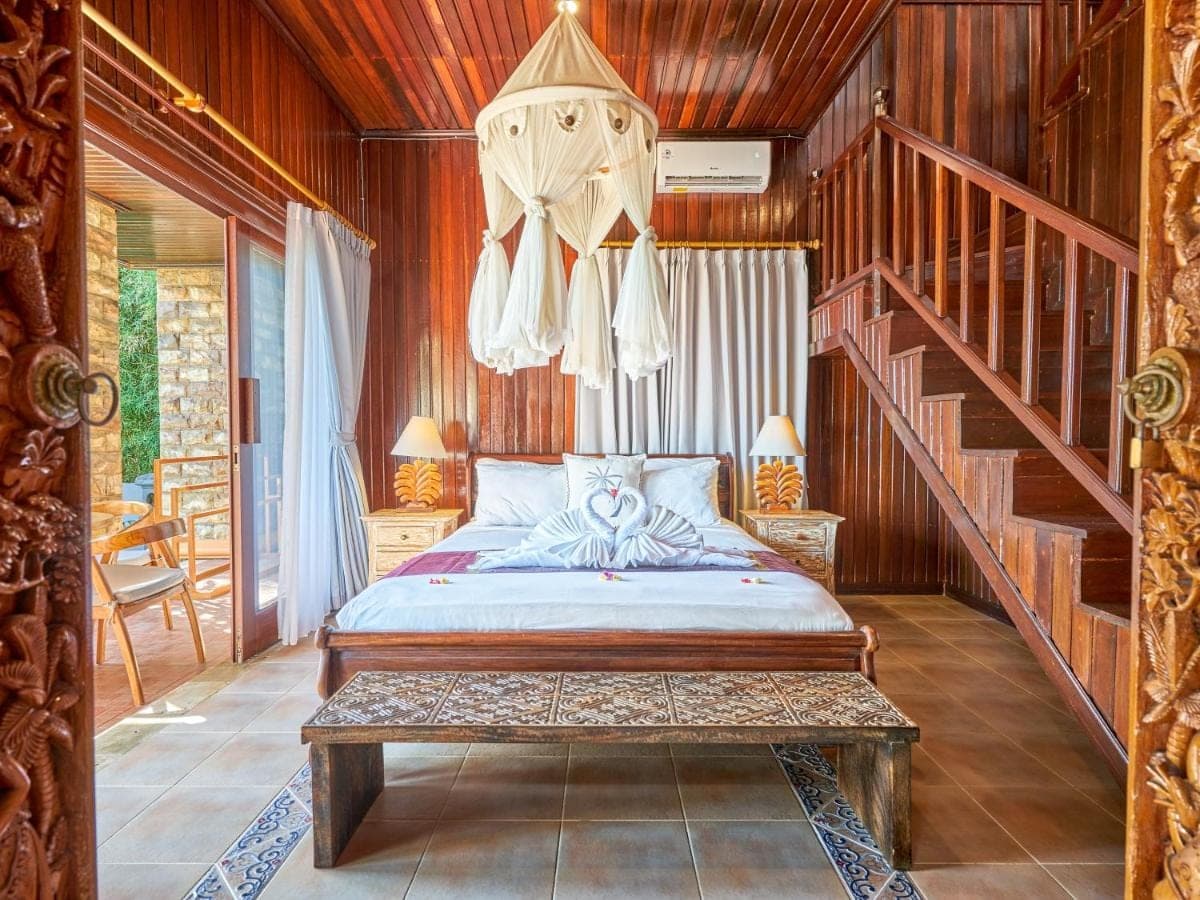 a bedroom with a bed and a stair case at Onlyou Villas in Amed
