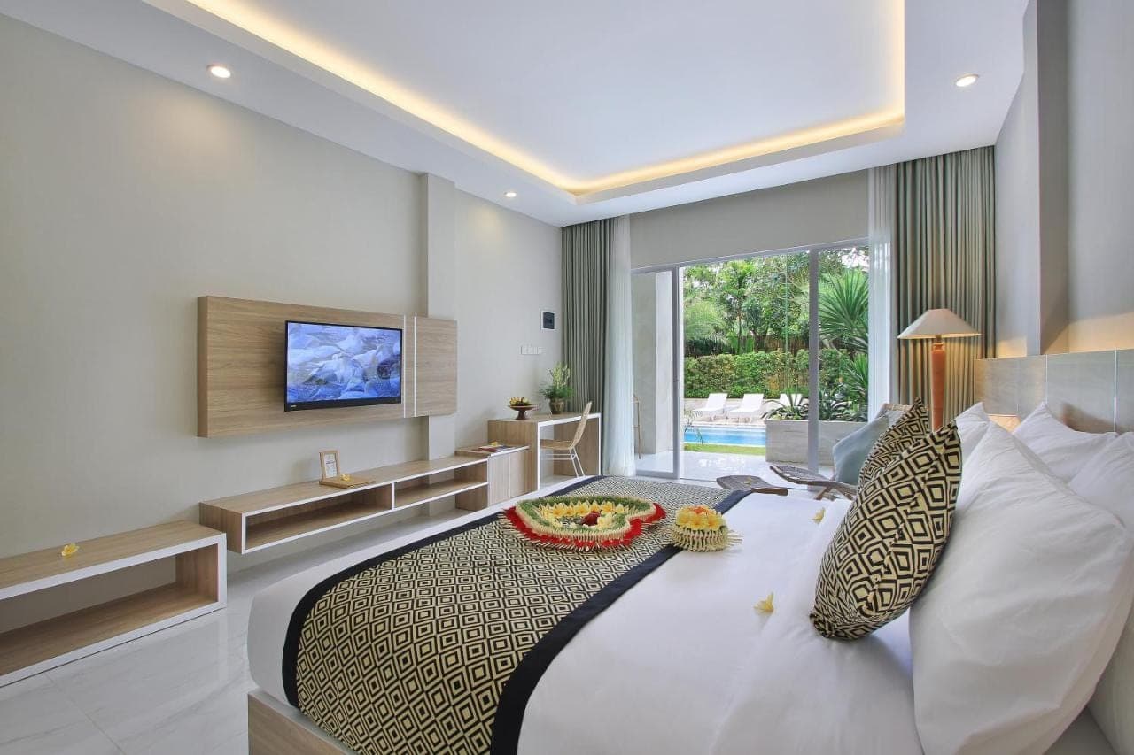 a hotel room with a bed and a television at Tapa Tepi Kali Canggu in Canggu