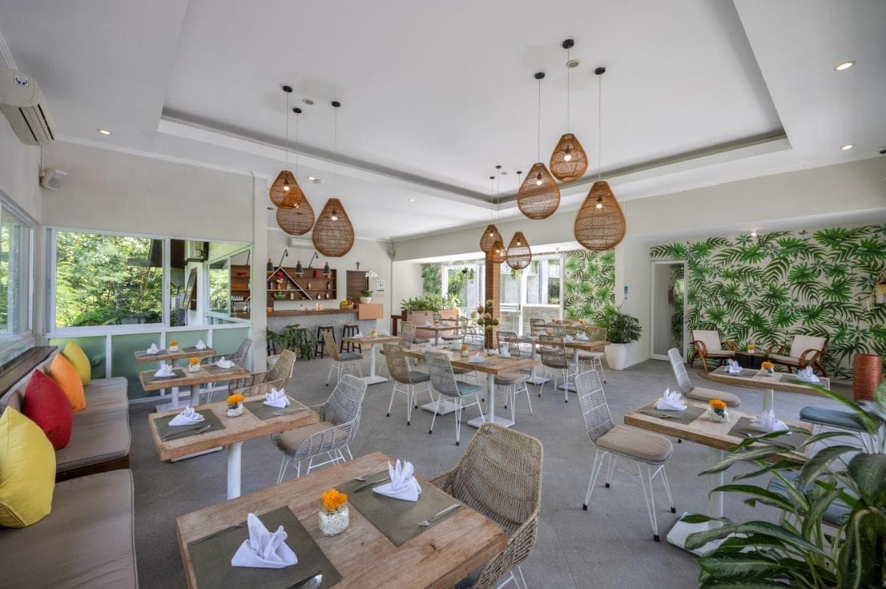 a restaurant with tables and chairs and windows at Tapa Tepi Kali Canggu in Canggu