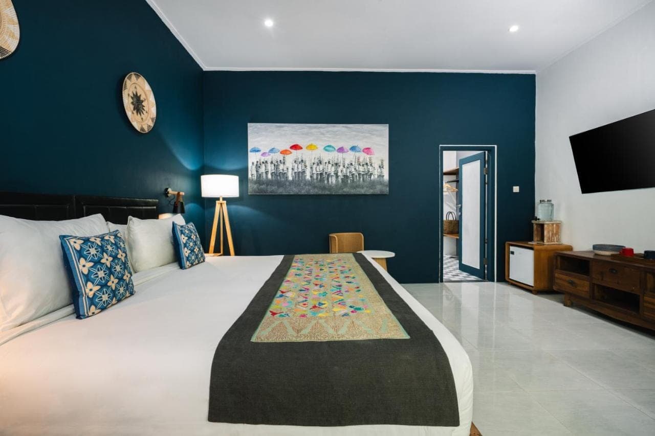 a bedroom with a large bed with blue walls at Sanur House in Sanur