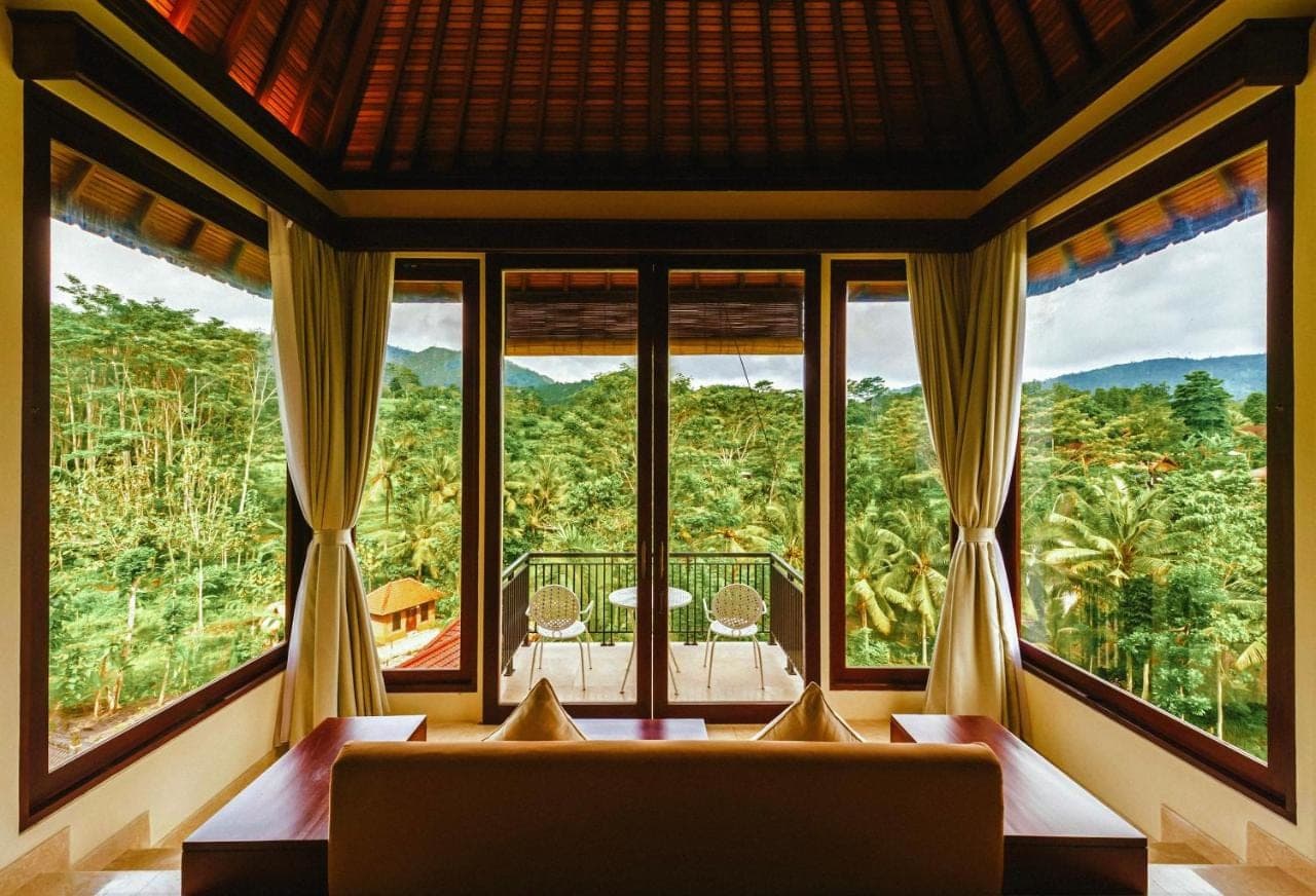 a living room with a couch and large windows at Cepik Villa Sidemen by AGATA in Sidemen