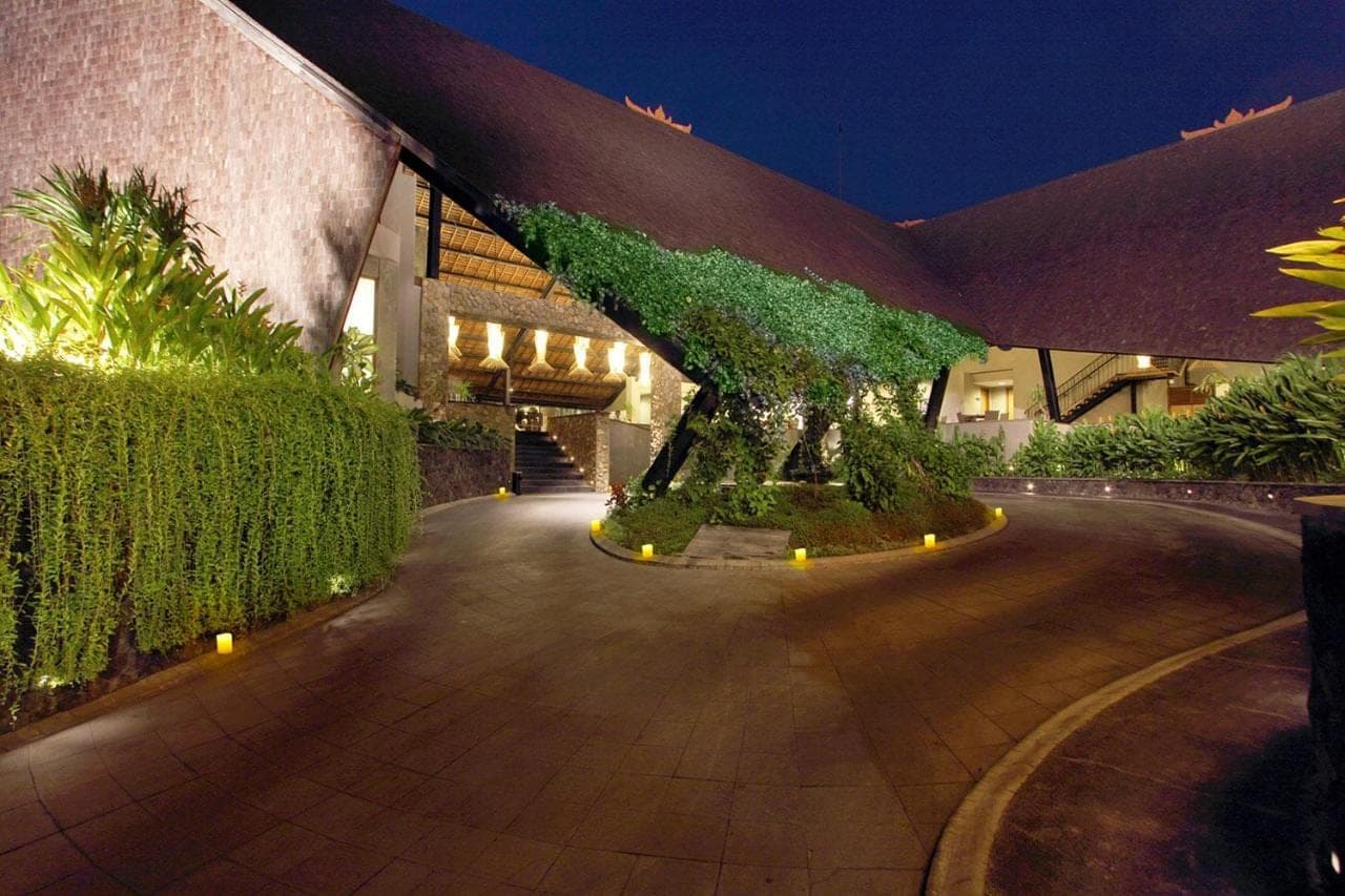 a building with a tree in the middle of a road at THE 1O1 Bali Oasis Sanur in Sanur