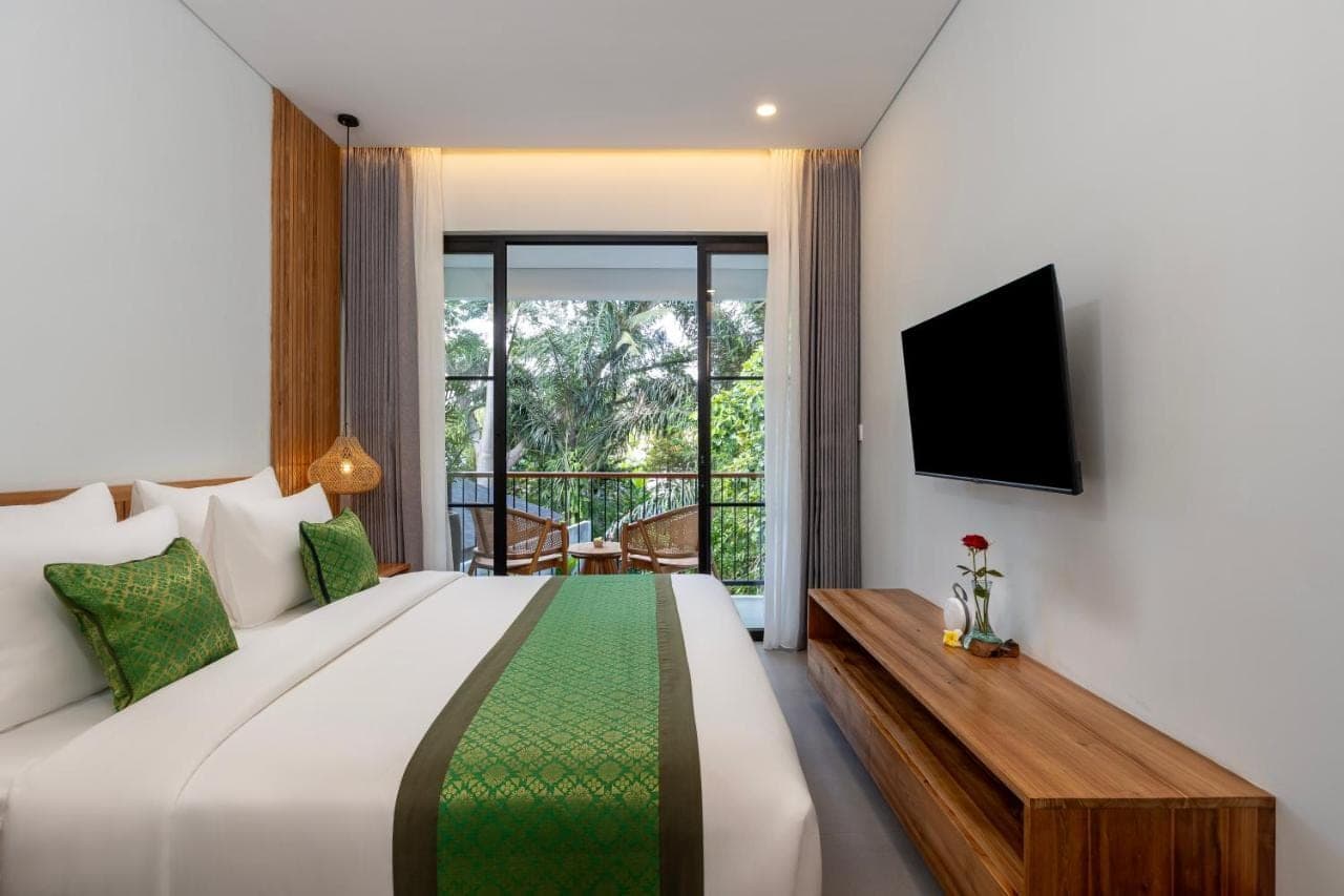 a bedroom with a large bed and a balcony at Elitya Ubud Cottage in Ubud
