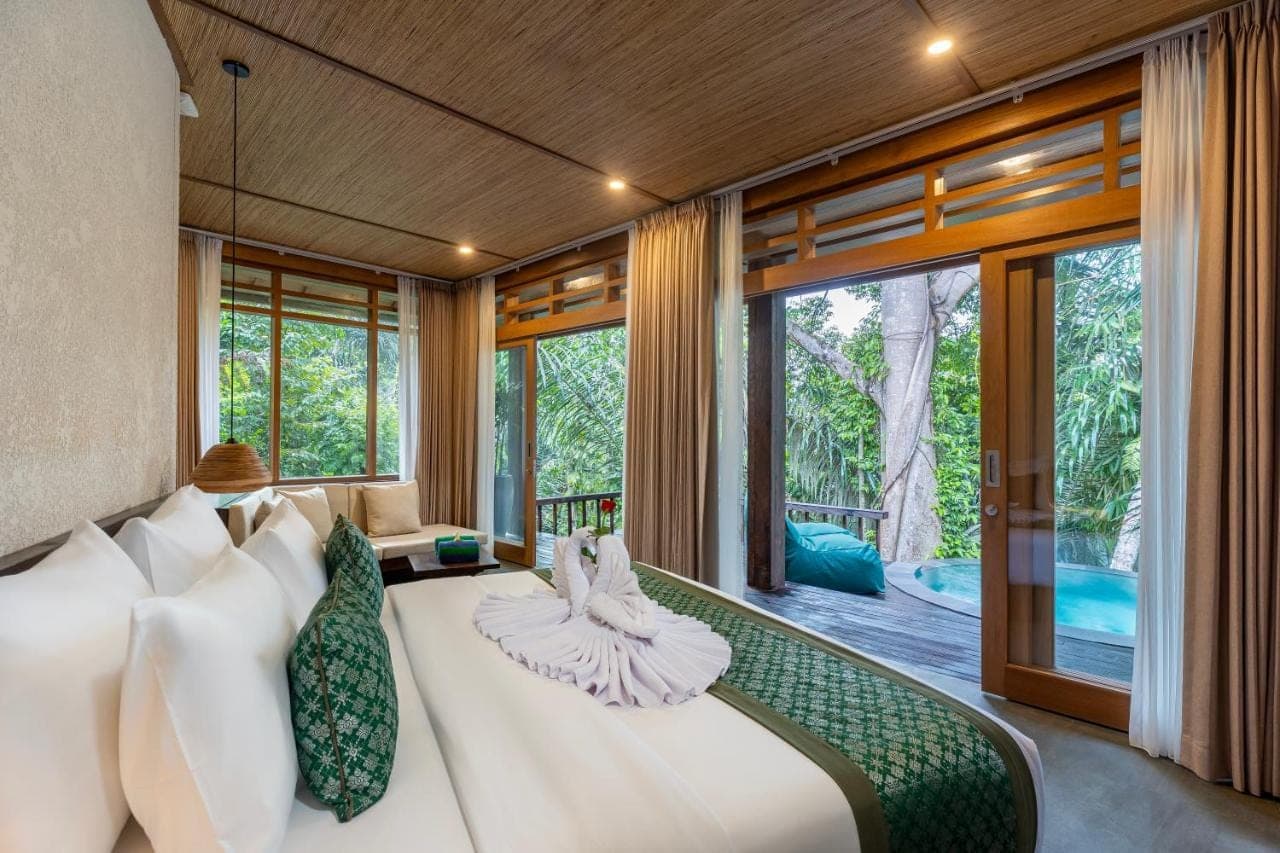 a bedroom with a large bed in a room with windows at Elitya Ubud Cottage in Ubud