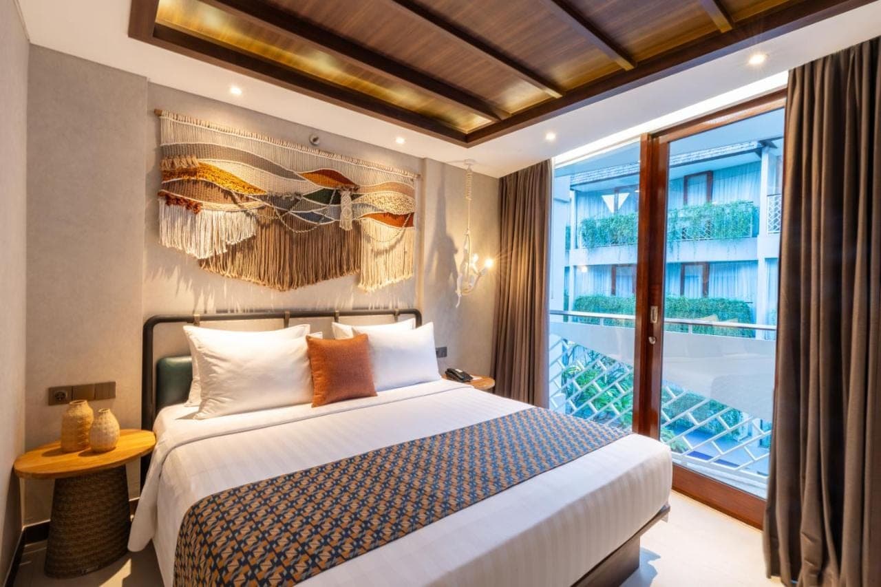 a bedroom with a bed and a large window at Episode Kuta Bali in Kuta