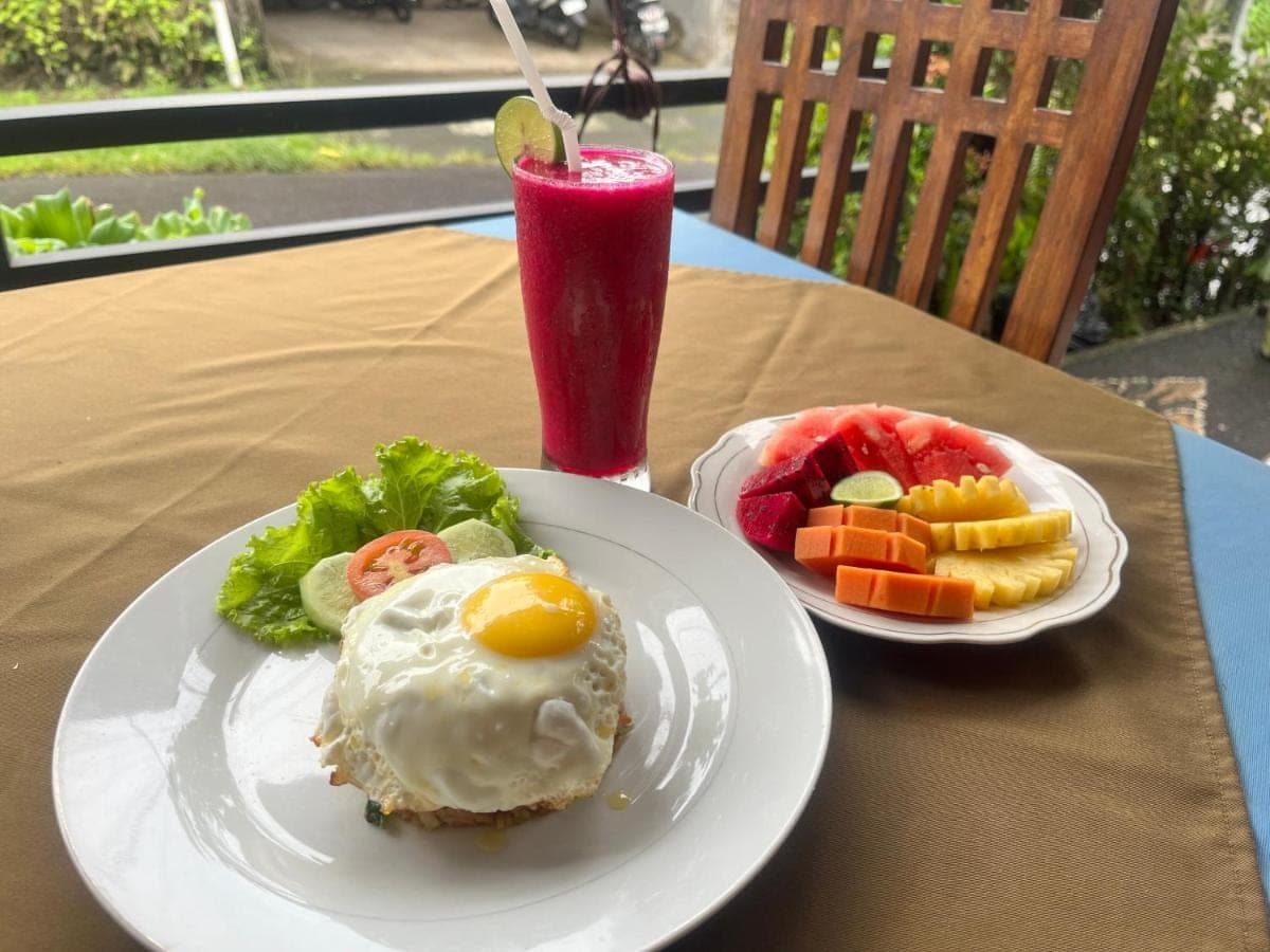 a table with two plates of food and a drink at Lumbung Kembar Sidemen in Sidemen