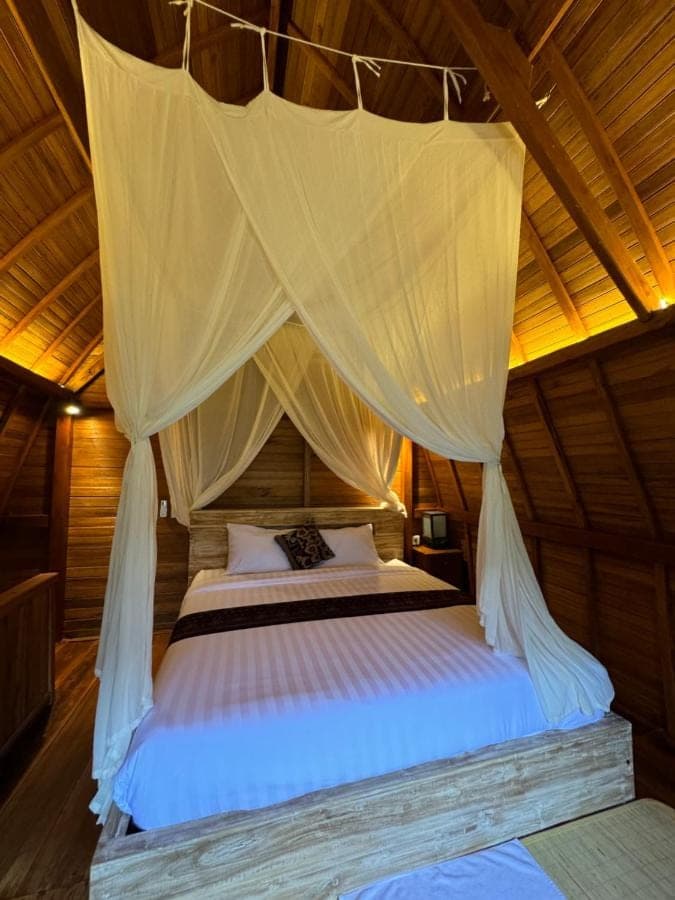 a bed in a room with a canopy at Lumbung Kembar Sidemen in Sidemen