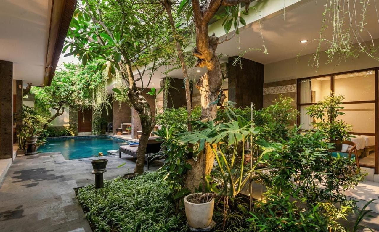 a house with a pool and trees and plants at Naksa Homestay Sanur in Sanur