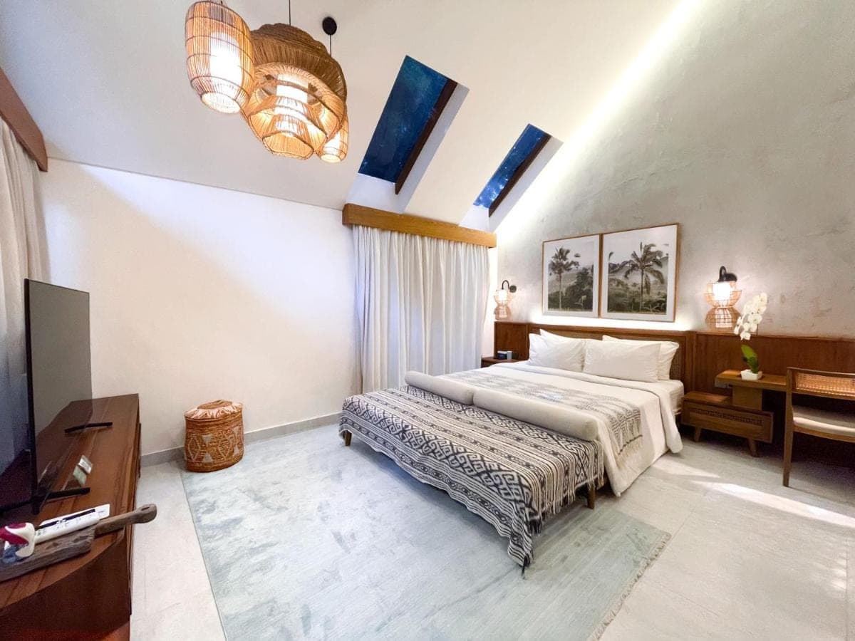 a bedroom with a bed and a desk and a television at Leafy Home Canggu - 5 Mins Walk to Echo Beach in Canggu
