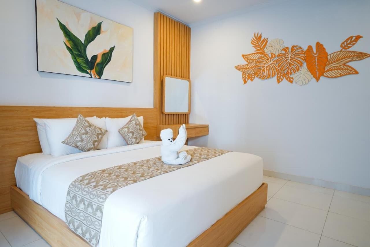a white teddy bear sitting on a bed in a bedroom at La Tierra Canggu in Canggu