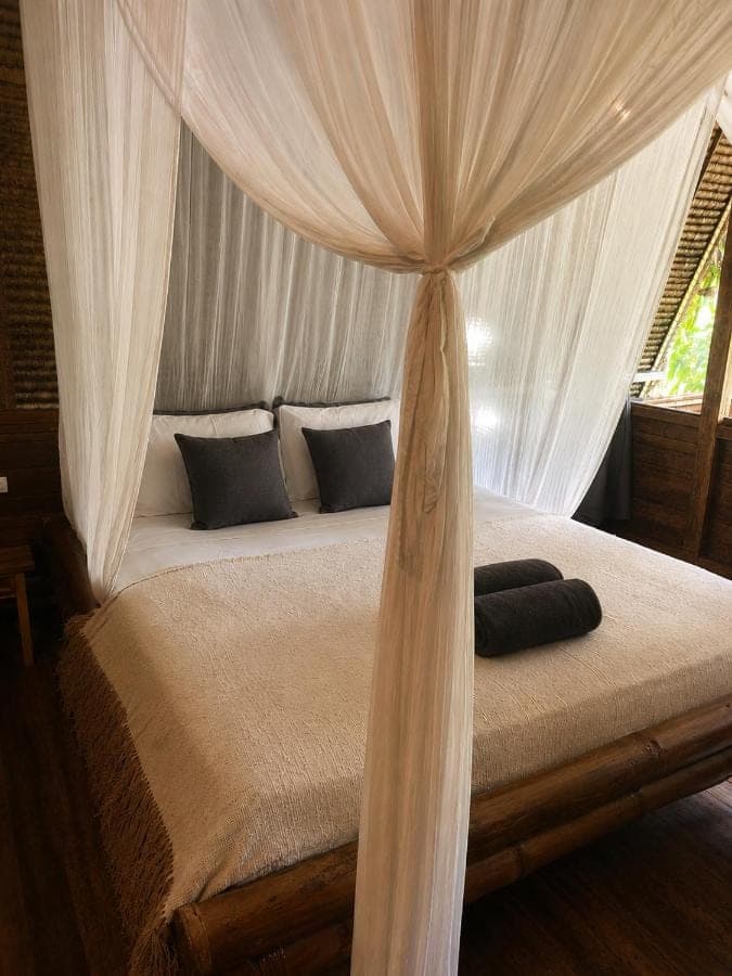 a bedroom with a canopy bed with curtains at Vertical House Bali in Uluwatu