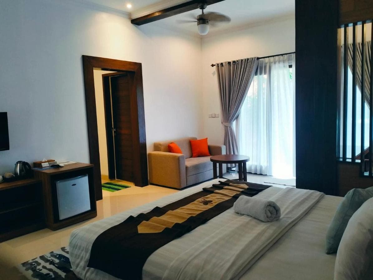 a bedroom with a large bed and a tv at Mandox Bali Homestay in Nusa Dua