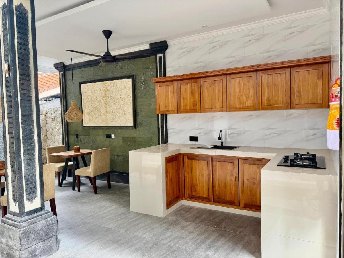 a kitchen with wooden cabinets and a table at Eva Guest House in Canggu