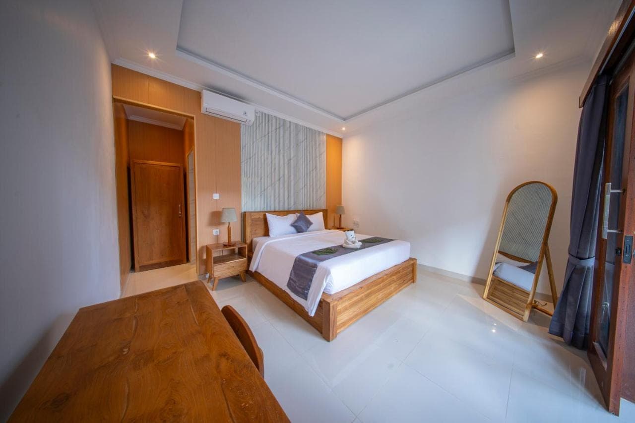 a bedroom with a bed and a wooden table at Eva Guest House in Canggu