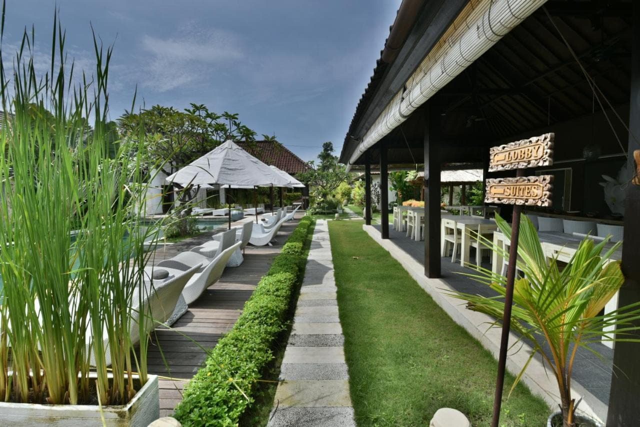 a resort with a row of white benches and grass at Katala Suites and Villas in Sanur