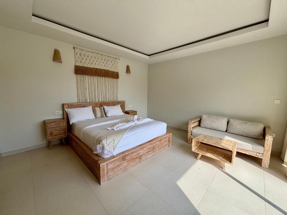a bedroom with a bed and a bench in it at Lipah Beach Private Villas in Amed