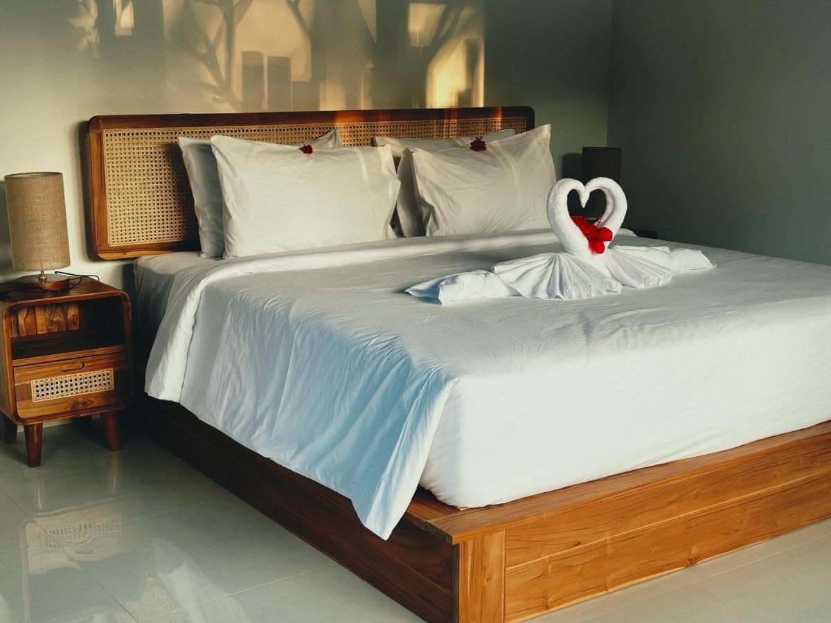 a white bed with a swan decoration on it at Made Putu homestay in Sidemen