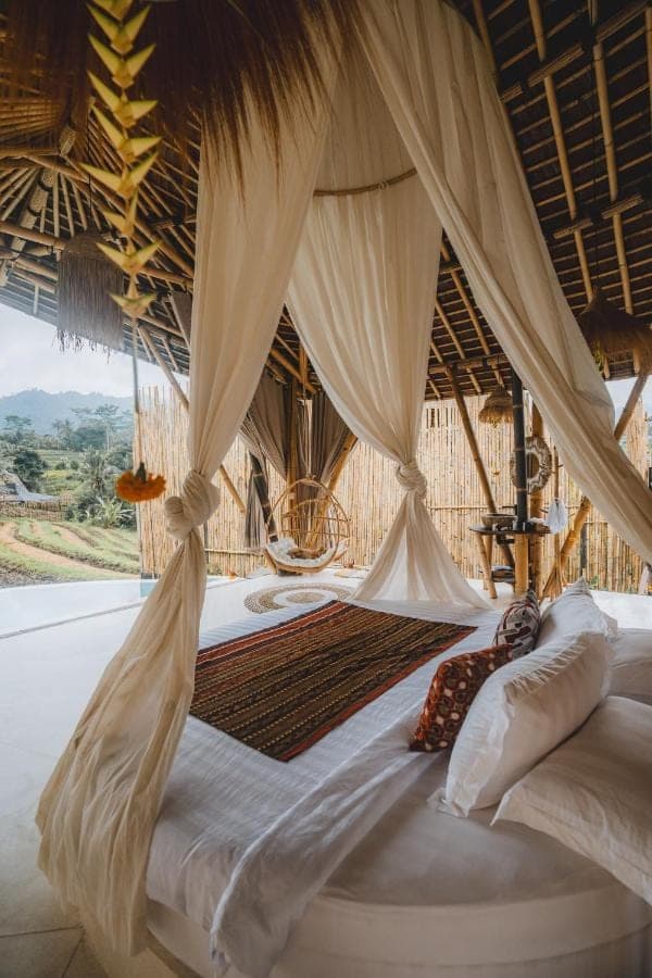 a bedroom with a canopy bed with a large window at Nivriti Bali in Sidemen