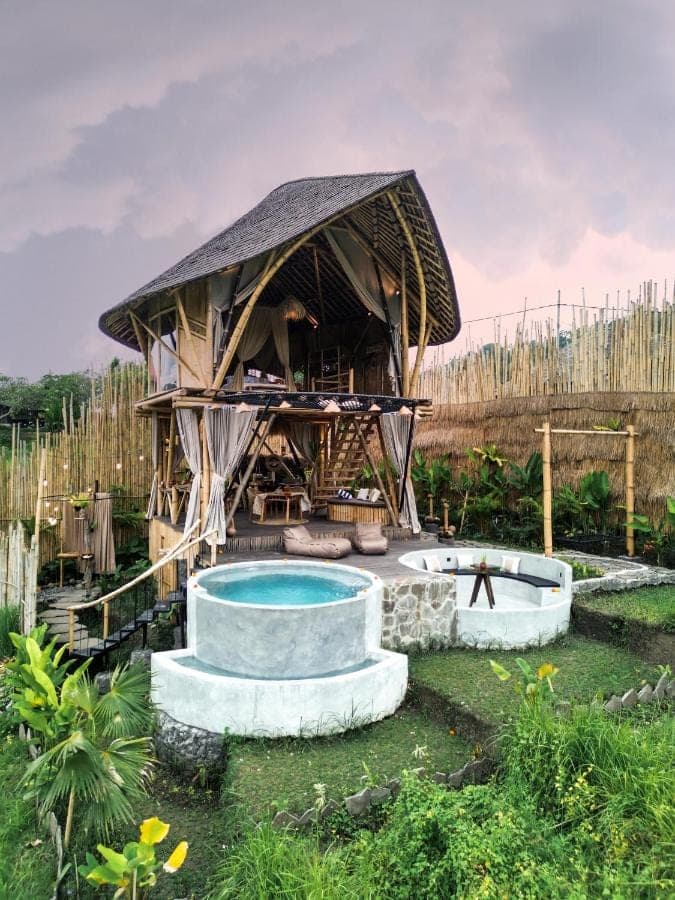 a large building with a swimming pool in a yard at Nivriti Bali in Sidemen