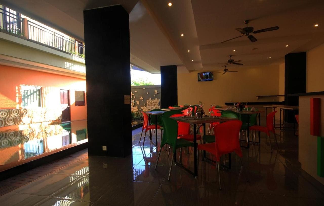 a restaurant with green tables and red chairs at The Agung Residence in Seminyak