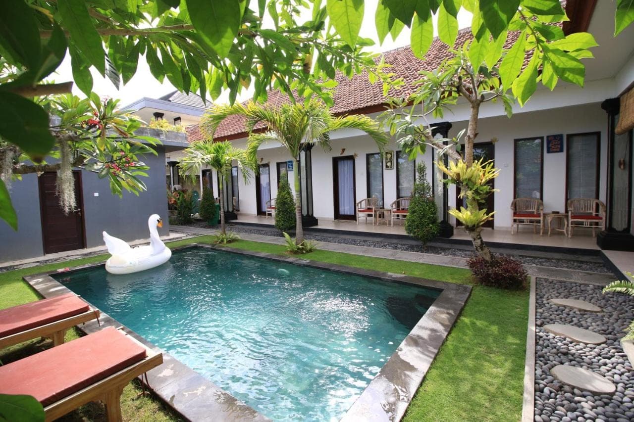 a pool in the backyard of a house with a swan in the water at Surf Lodge Canggu in Canggu