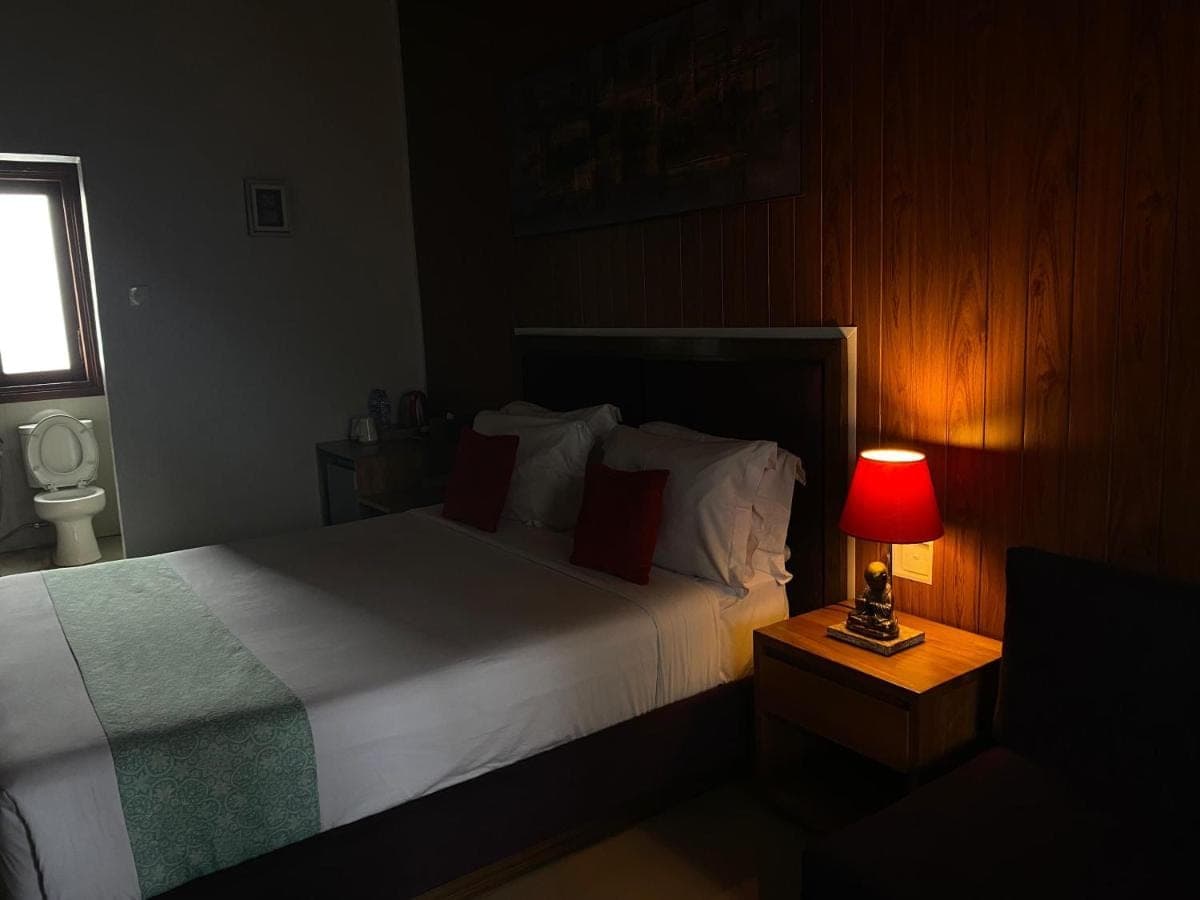 a bedroom with a bed with a red lamp on a table at Dikubu Belong Seminyak in Seminyak