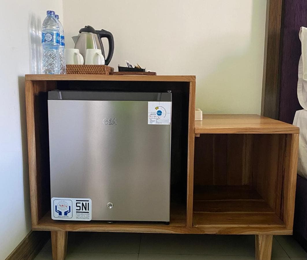 a small refrigerator in a wooden cabinet with a shelf at Dikubu Belong Seminyak in Seminyak