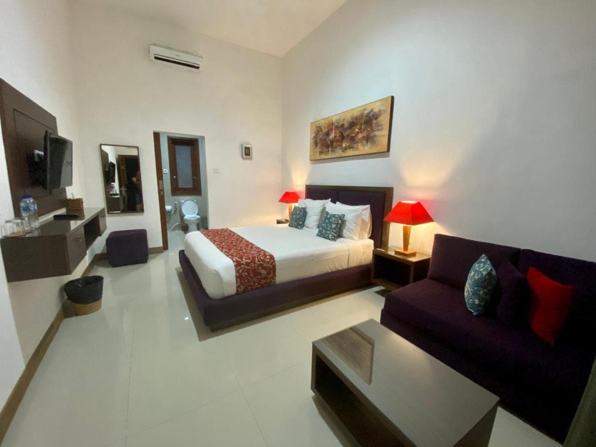 a hotel room with a bed and a couch at Dikubu Belong Seminyak in Seminyak