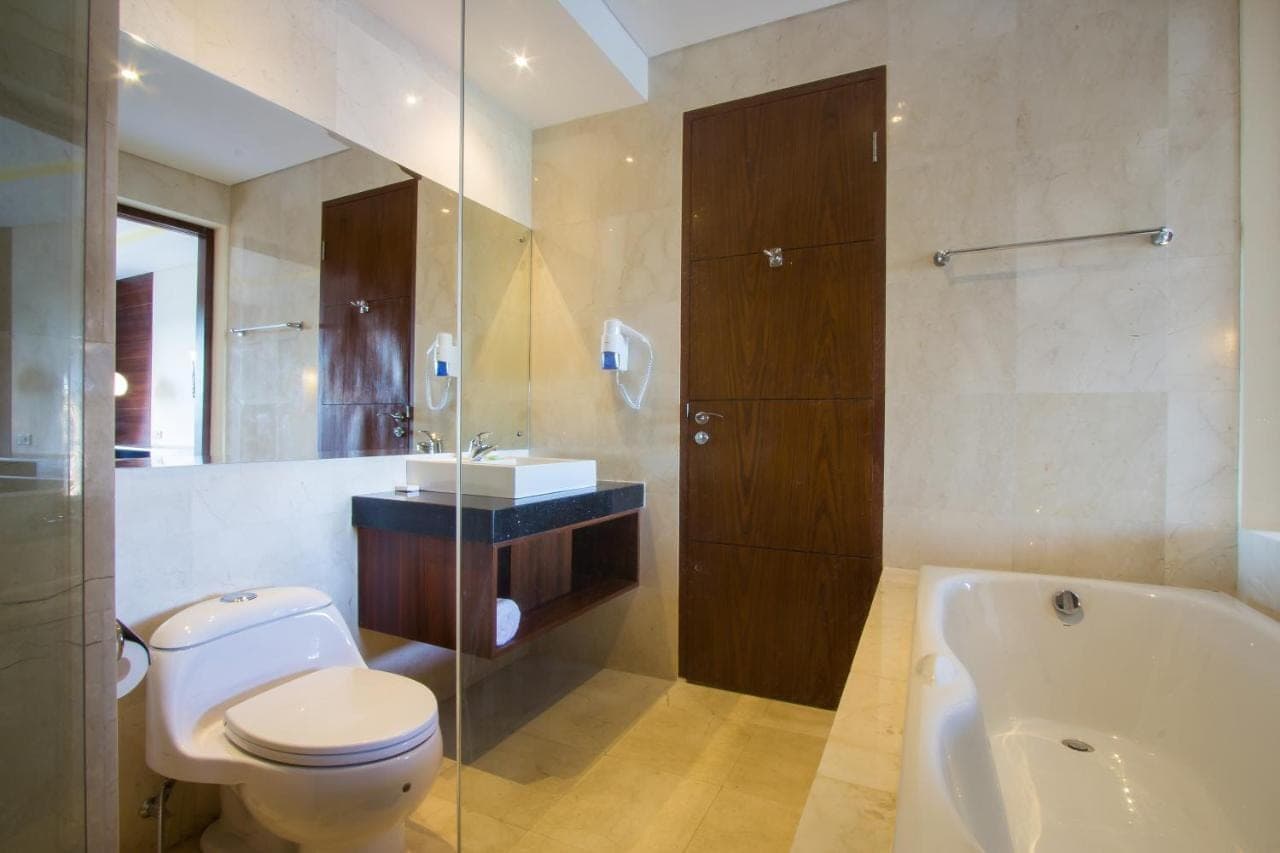 a bathroom with a toilet and a sink and a tub at M Suite Bali in Seminyak