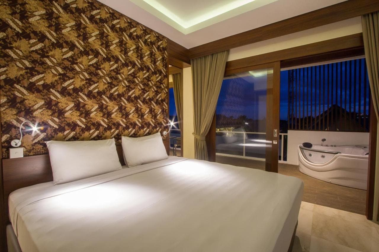 a bedroom with a large bed and a large window at M Suite Bali in Seminyak