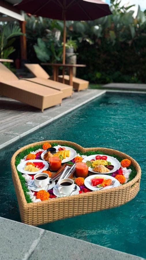a tray of food in a basket next to a swimming pool at Denaya Ubud Villa in Ubud