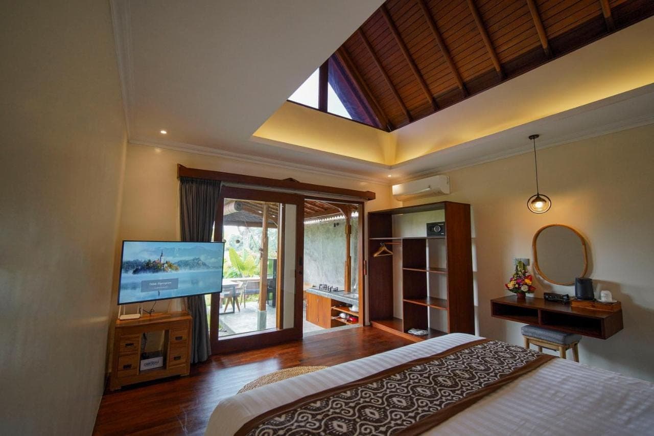 a bedroom with a large bed and a television at Denaya Ubud Villa in Ubud