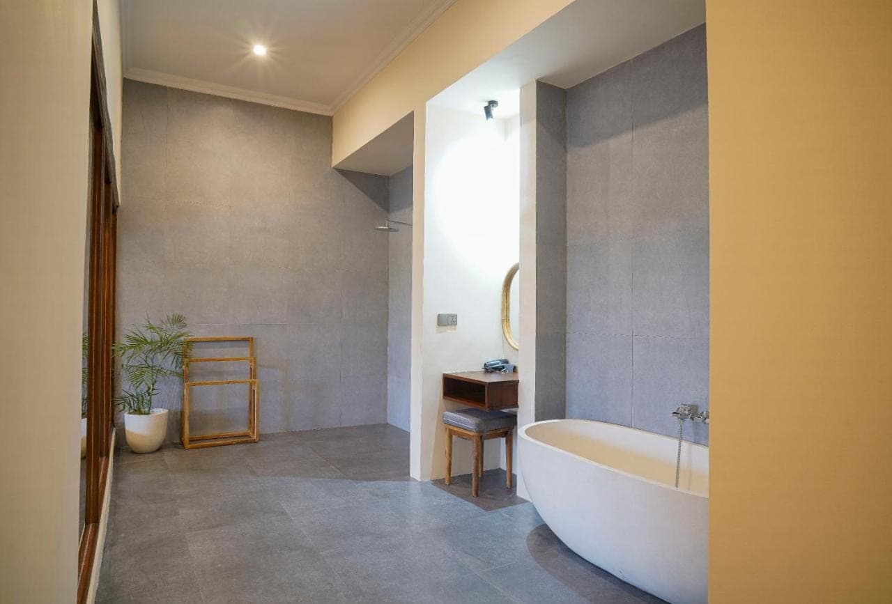 a bathroom with a tub and a table and a sink at Denaya Ubud Villa in Ubud