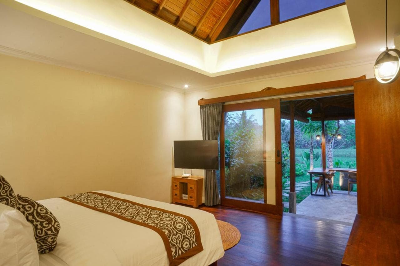 a bedroom with a bed and a sliding glass door at Denaya Ubud Villa in Ubud